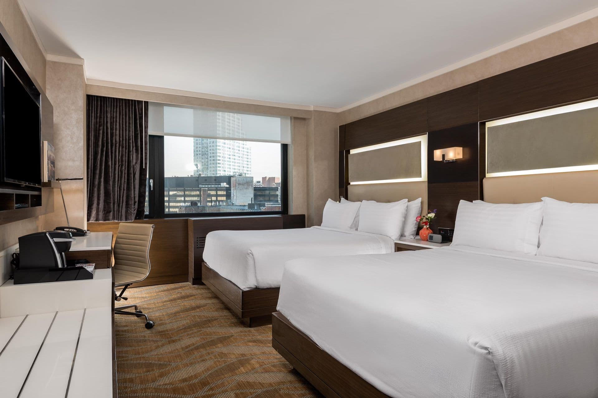 Modern hotel room with two queen beds, a desk, and city view, suitable for corporate event overnight stays.