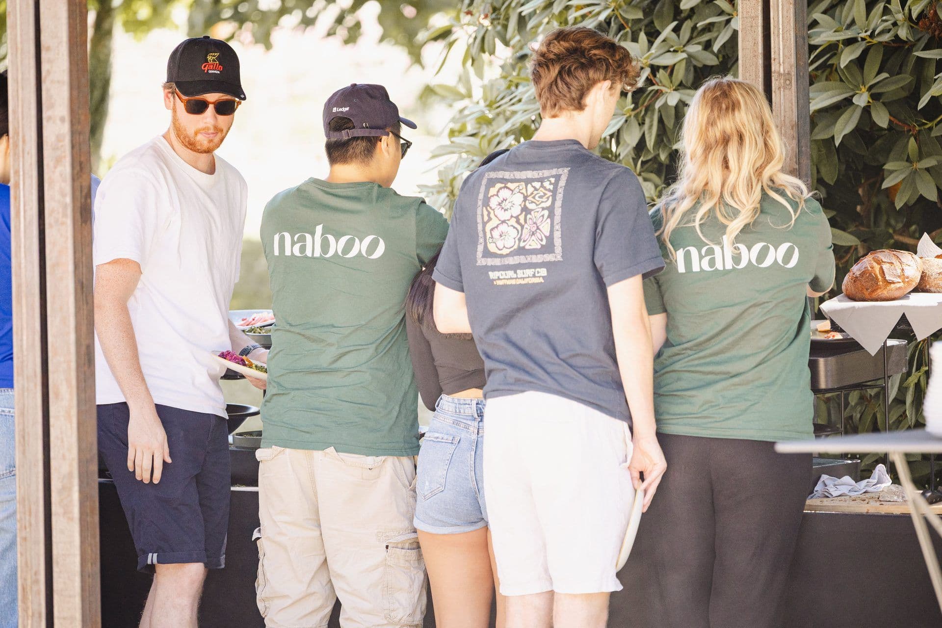 Guests enjoy a casual business lunch at an outdoor team offsite, with Naboo branded staff.