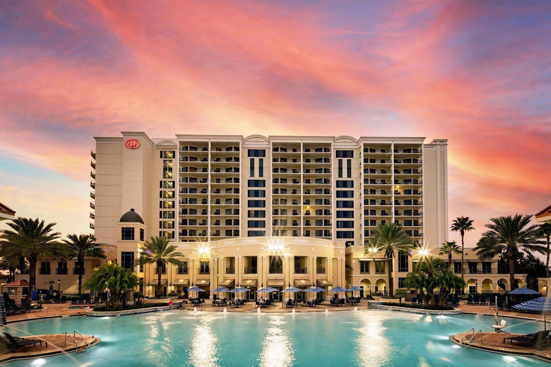 Luxury hotel with a large outdoor pool and palm trees, ideal for a corporate retreat or offsite.