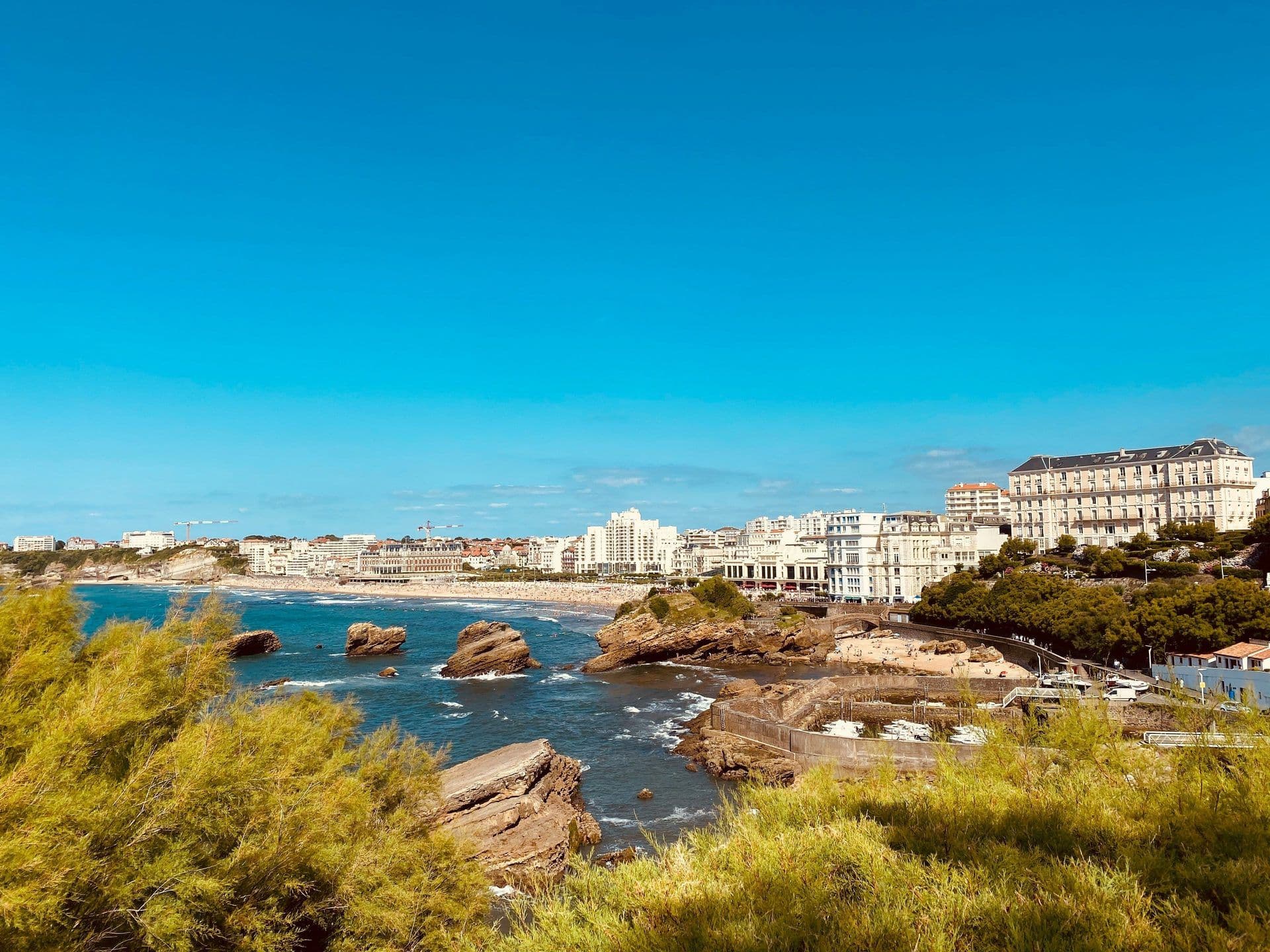 Biarritz coastline featuring a busy beach, rocky ocean, and historic waterfront buildings