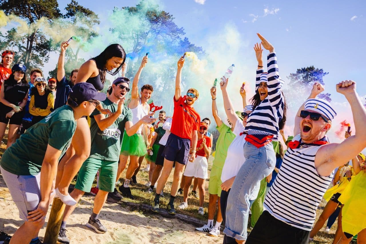 Large crowd of people celebrating with colored powder at outdoor festival in daylight