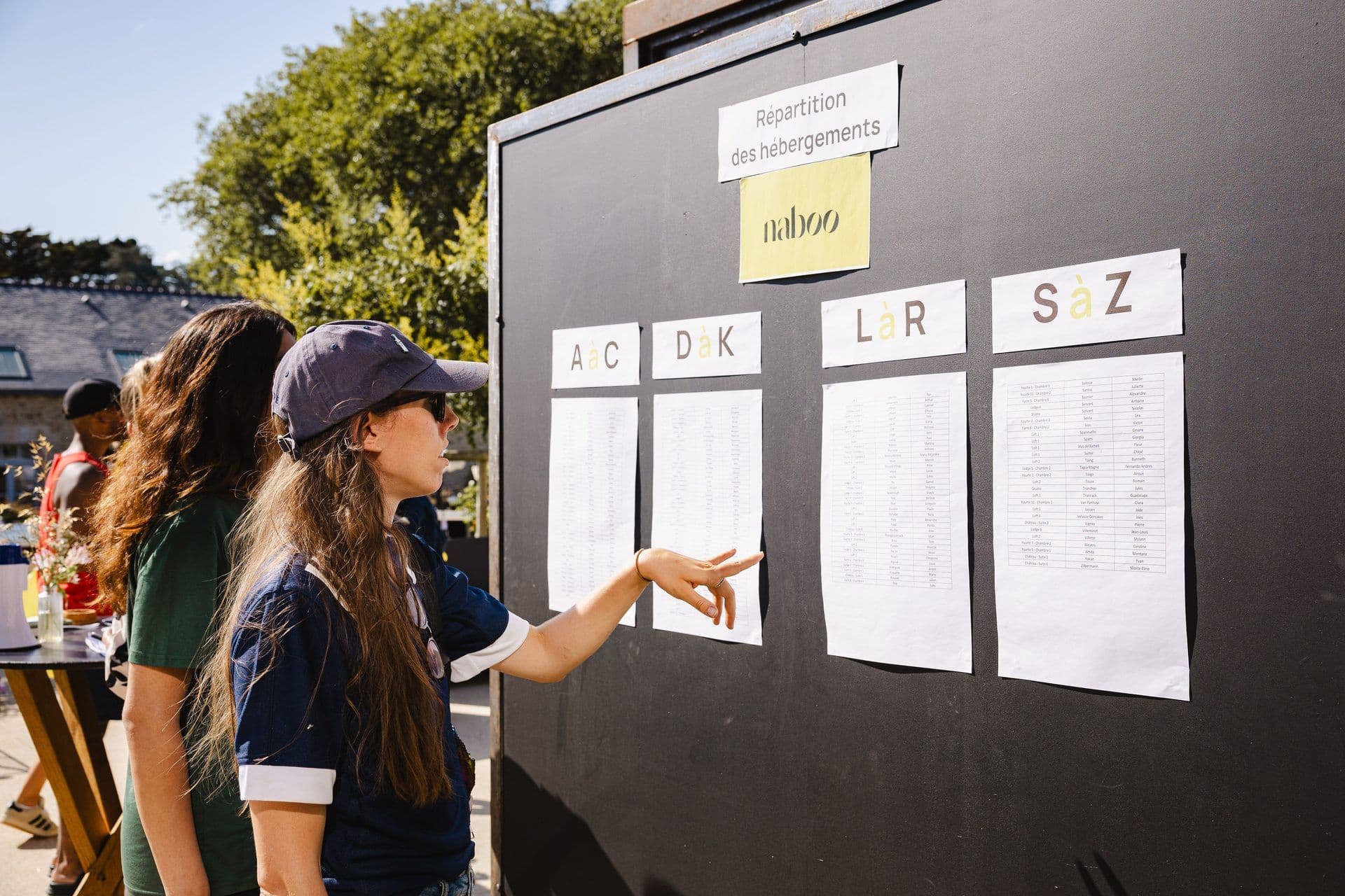 Woman points at an accommodation list for a residential corporate retreat or team offsite event outdoors.