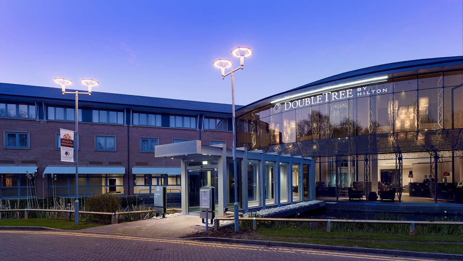 Exterior view of a modern DoubleTree by Hilton hotel at dusk, a prime corporate event venue.
