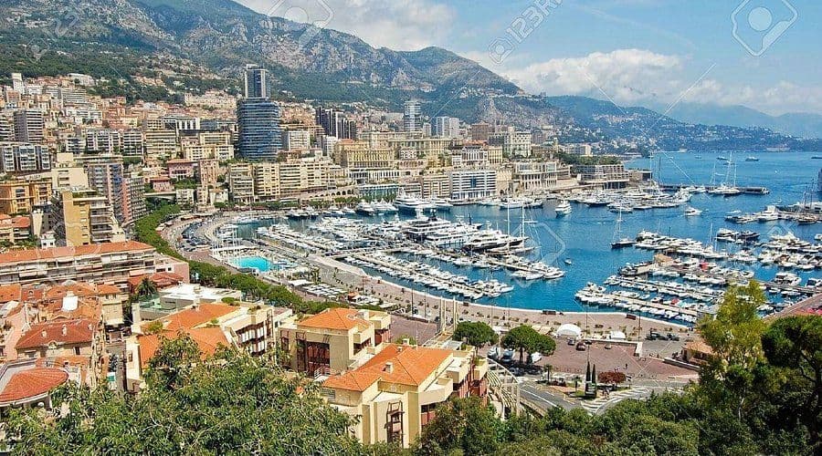 Panoramic view of Monte Carlo, Monaco, featuring a harbor filled with luxury yachts and coastal buildings.