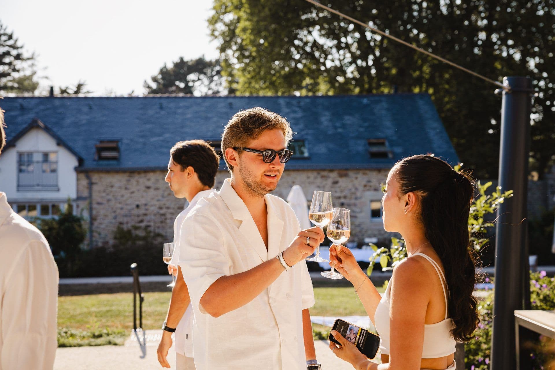 Two colleagues toast with white wine at an outdoor corporate networking reception.