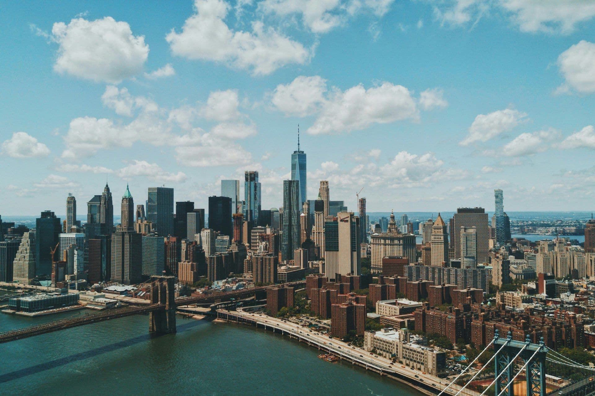 New York City skyline aerial view, showcasing skyscrapers, Brooklyn Bridge, and the East River