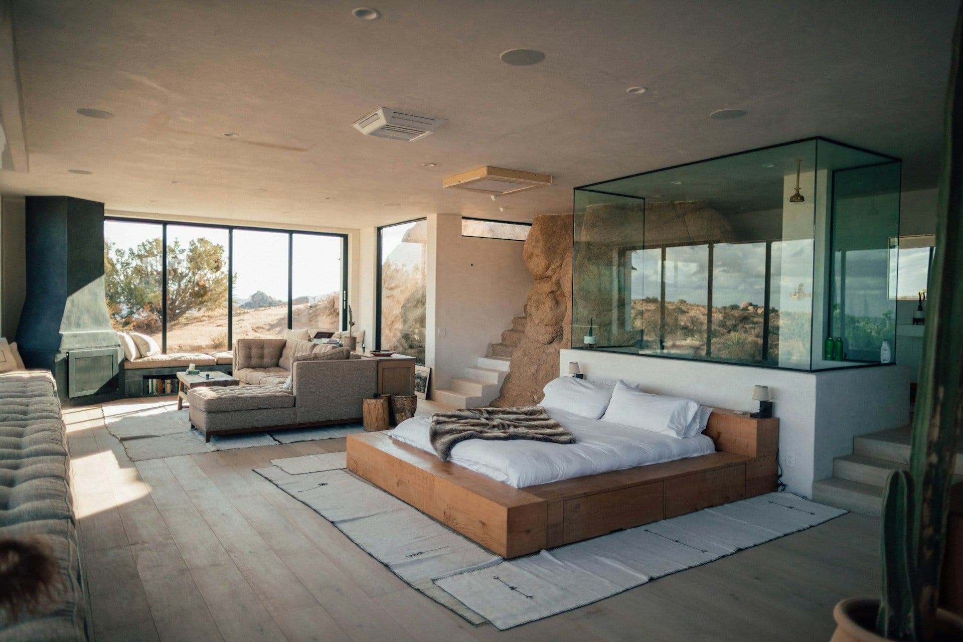 A modern, open-plan residential seminar venue featuring a bedroom, living space, and panoramic desert views.
