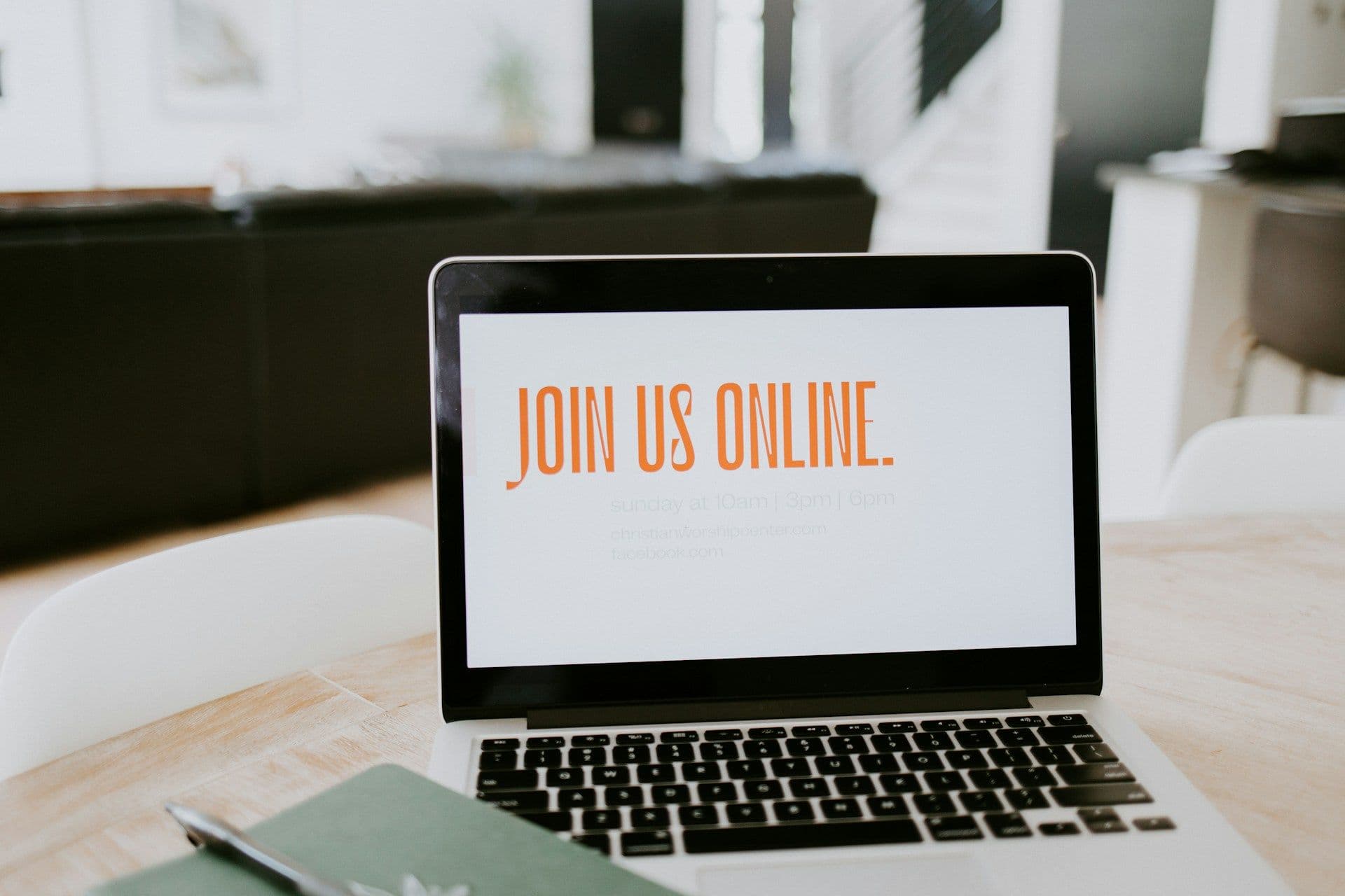 A laptop on a light wooden table displays 'JOIN US ONLINE' for a virtual corporate event.