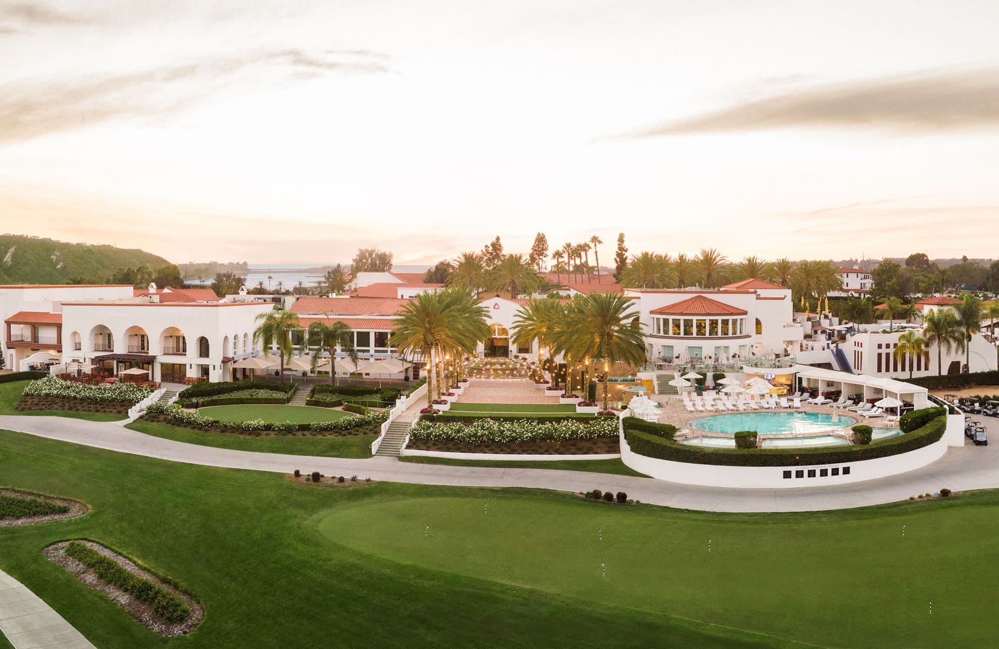 Aerial view of a large corporate event venue with white buildings, red roofs, palm trees, a pool