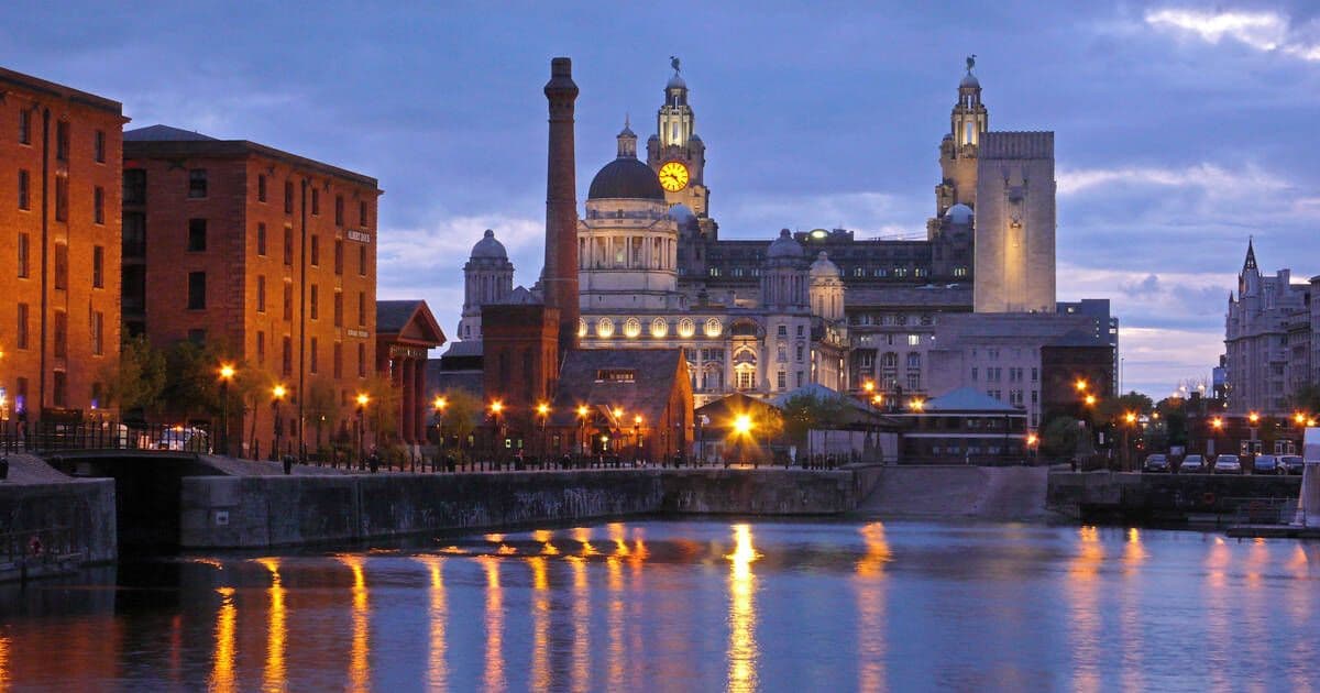 Illuminated historic waterfront venues and the Liver Building at dusk in Liverpool, UK.
