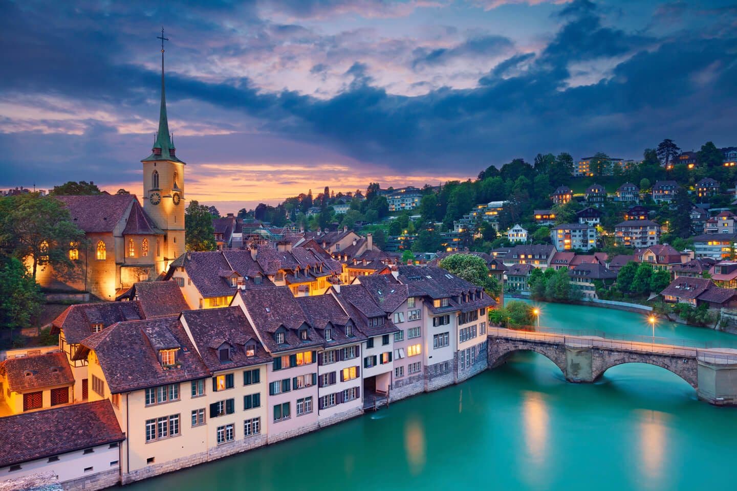 Historic Bern, Switzerland, showcasing a waterfront venue and old town at dusk with river and bridge.