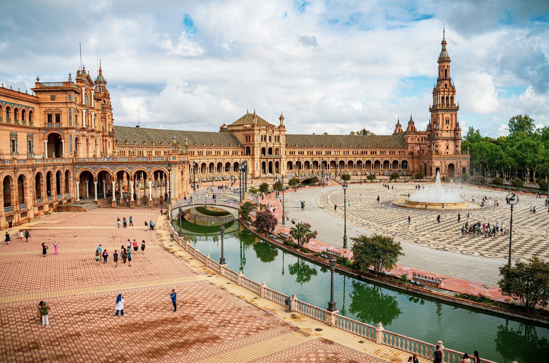 Grand historic venue, Plaza de España in Seville, Spain, with a canal, bridges, and fountain.