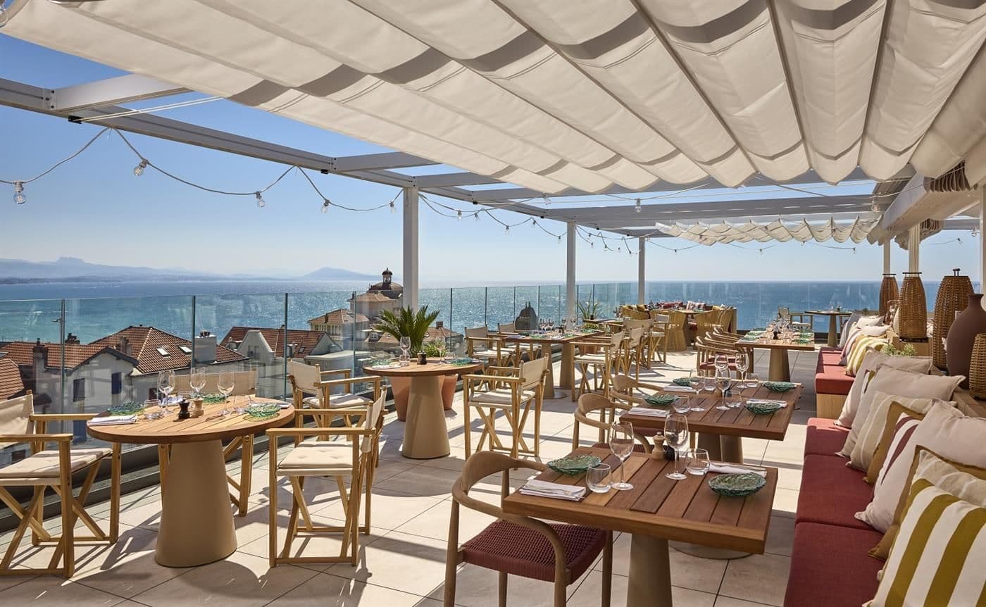 Outdoor rooftop event space with dining tables, a retractable awning