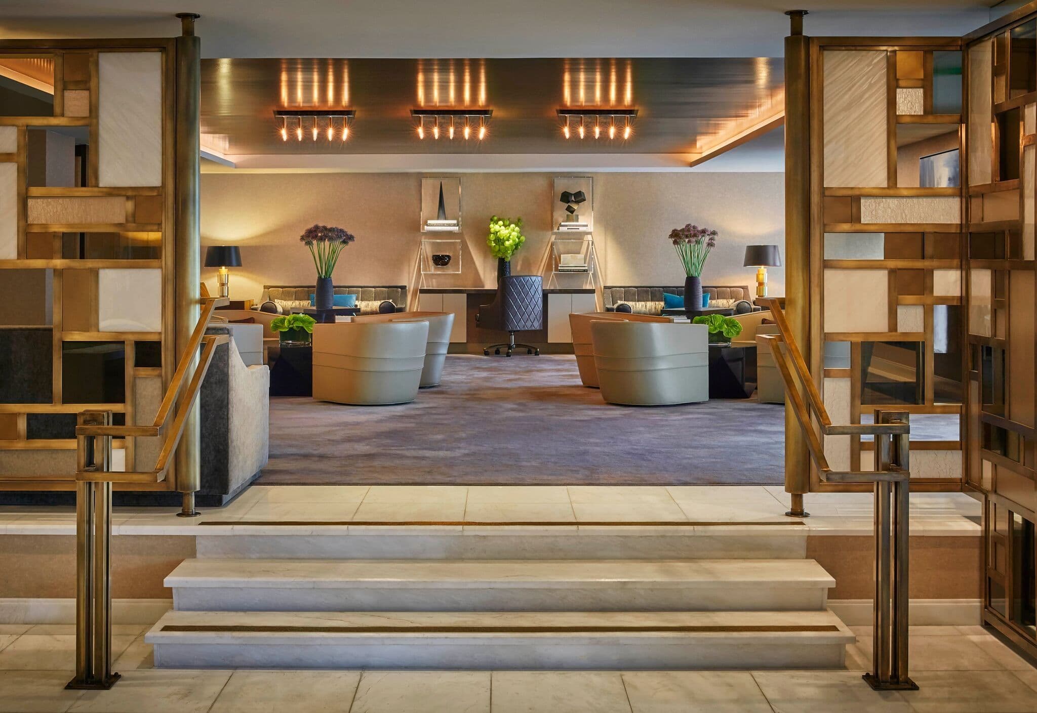 Elegant corporate event venue lounge featuring comfortable seating, a central desk, and warm ambient lighting.
