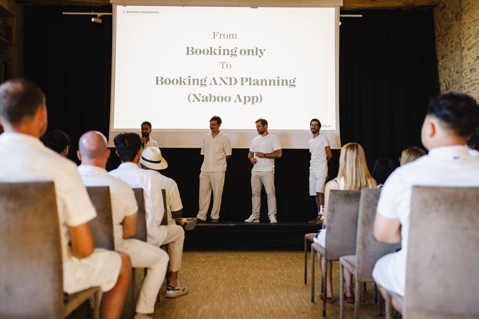 Four presenters on a stage address an audience during a corporate seminar in a unique historic venue.
