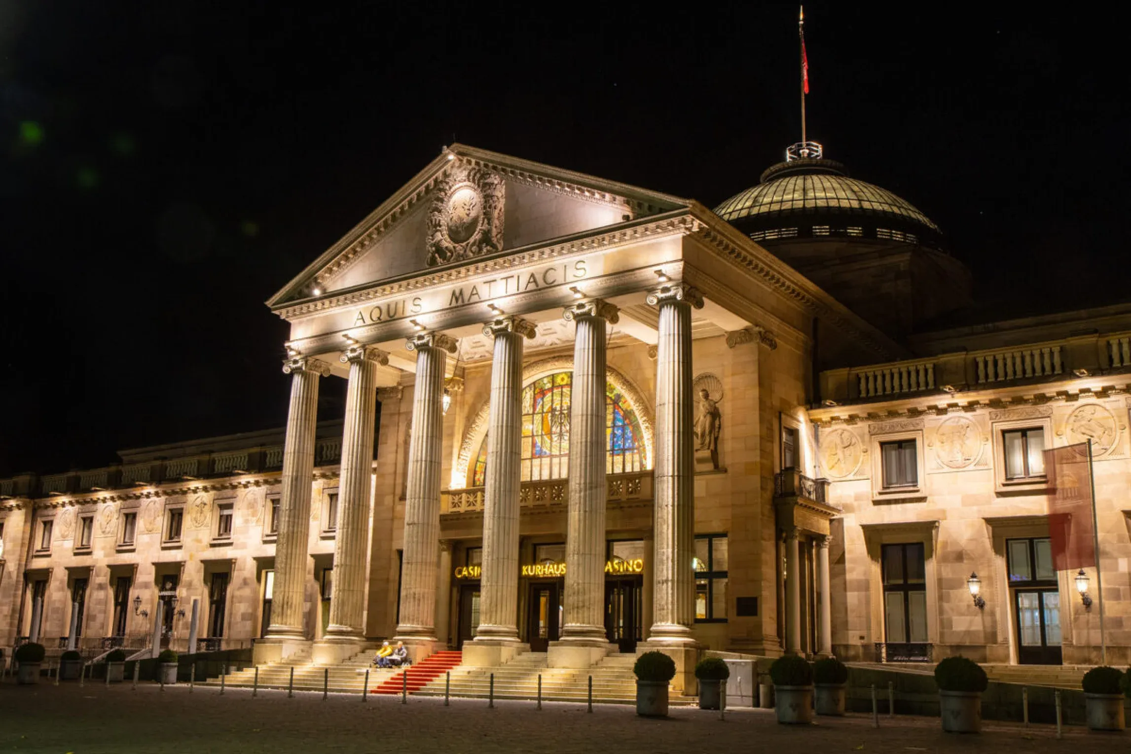 The illuminated Kurhaus Wiesbaden, a grand historic corporate event venue with classical columns and a dome.