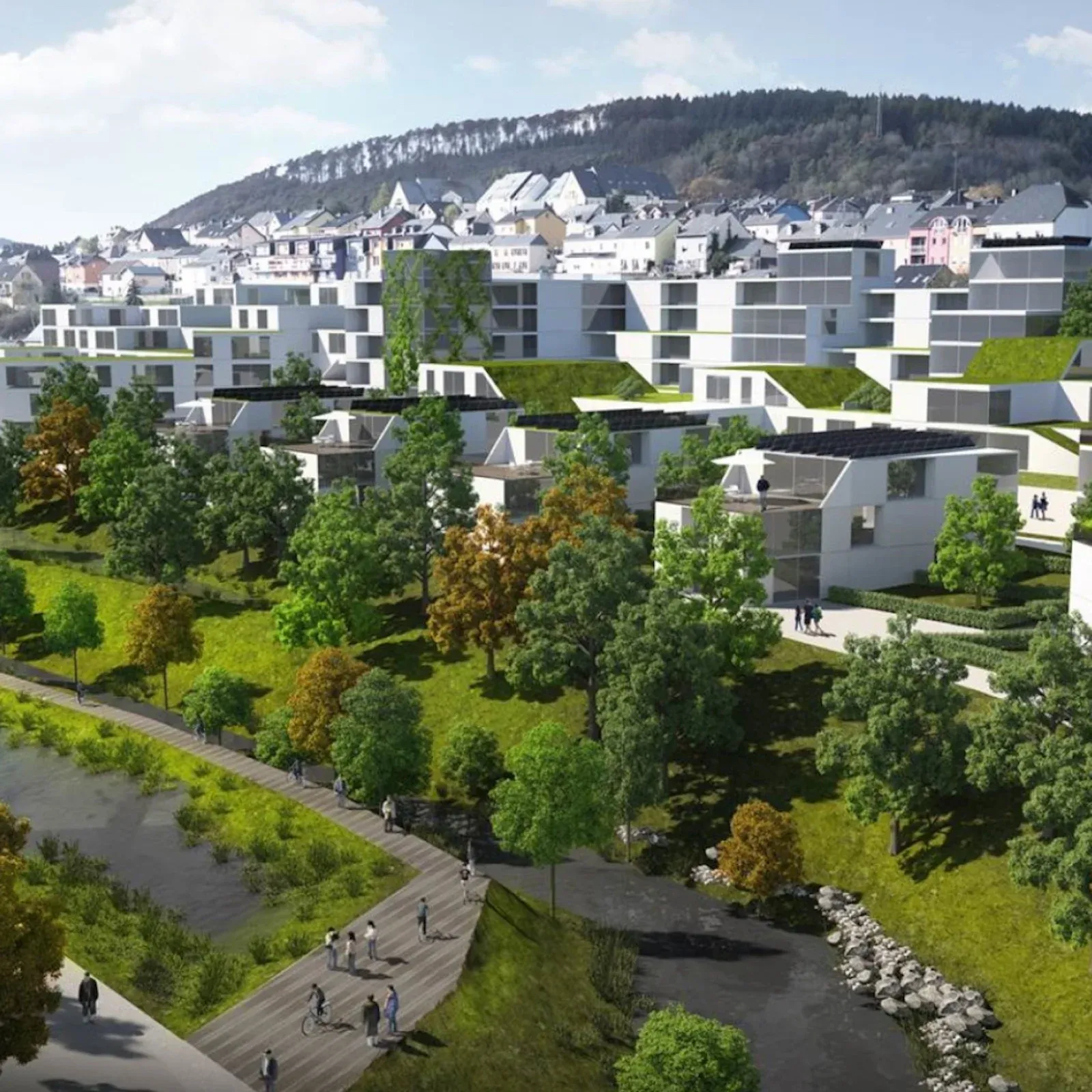 Modern eco-friendly buildings with green roofs and solar panels overlooking a river and hillside town in
