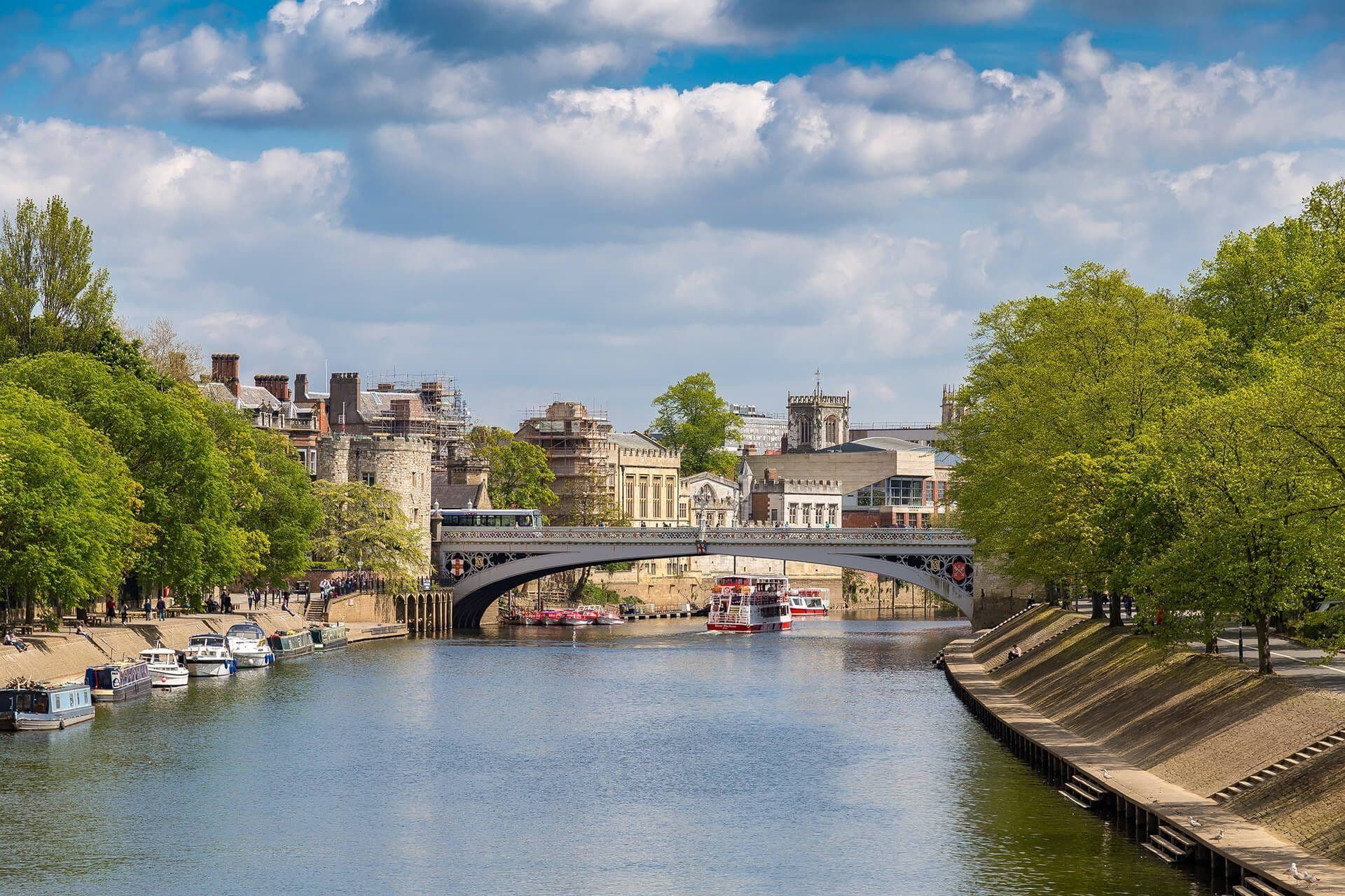 Historic York waterfront venue on the River Ouse, UK, with a bridge, city buildings, and boats.