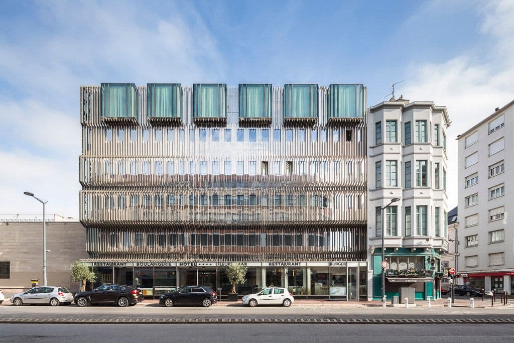 Modern 4-star hotel and restaurant building with a distinctive slatted facade in a French city.