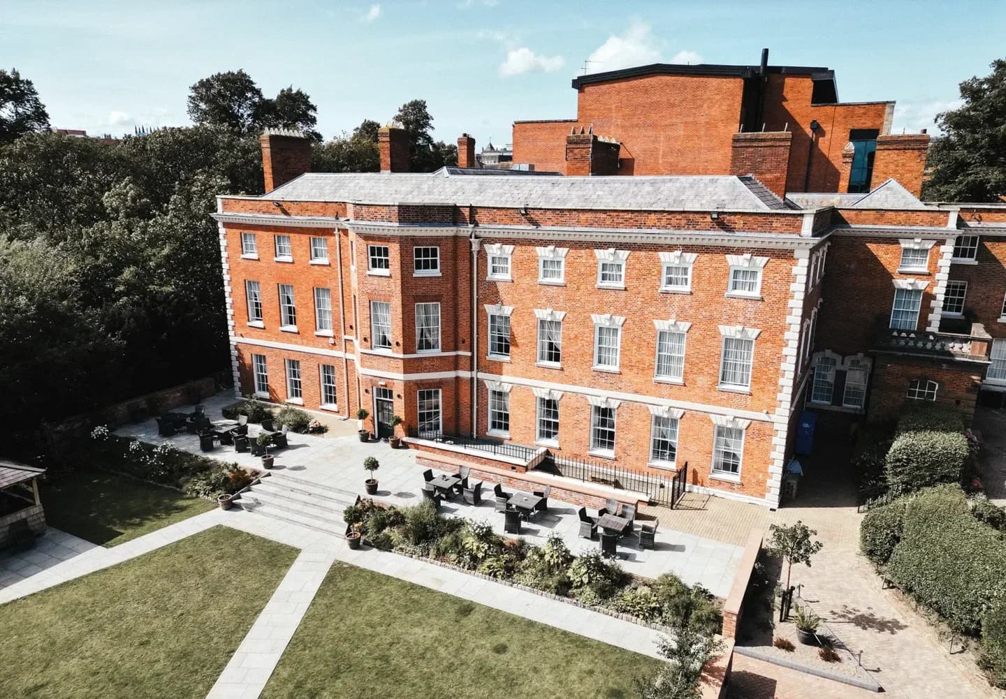 Aerial view of a historic red brick corporate event venue with an outdoor terrace and garden in Chester.