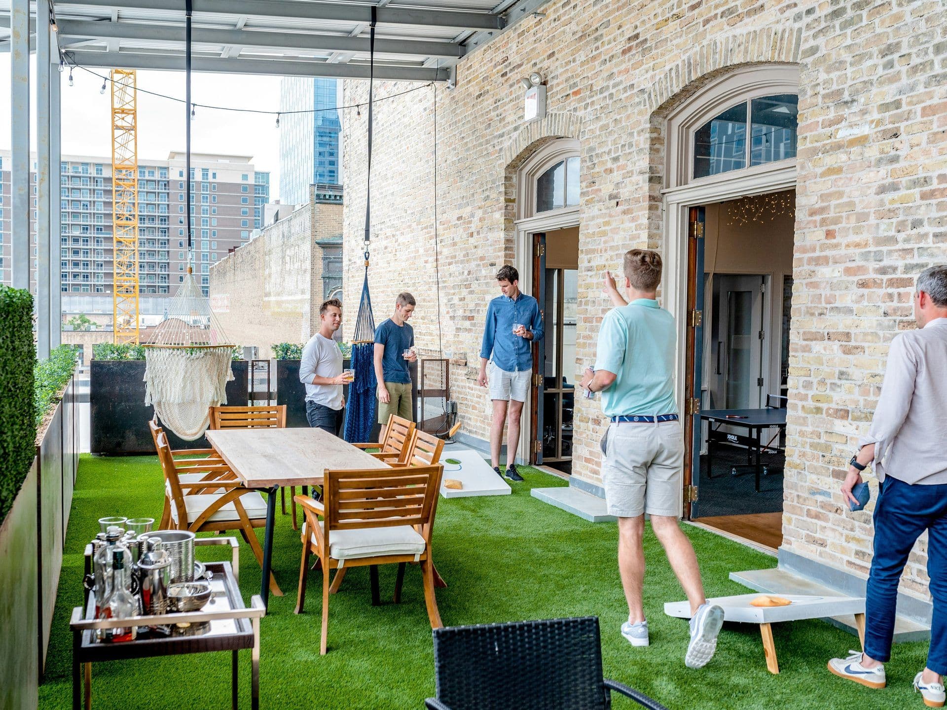 Colleagues enjoy an outdoor team building activity on a rooftop terrace with artificial grass.