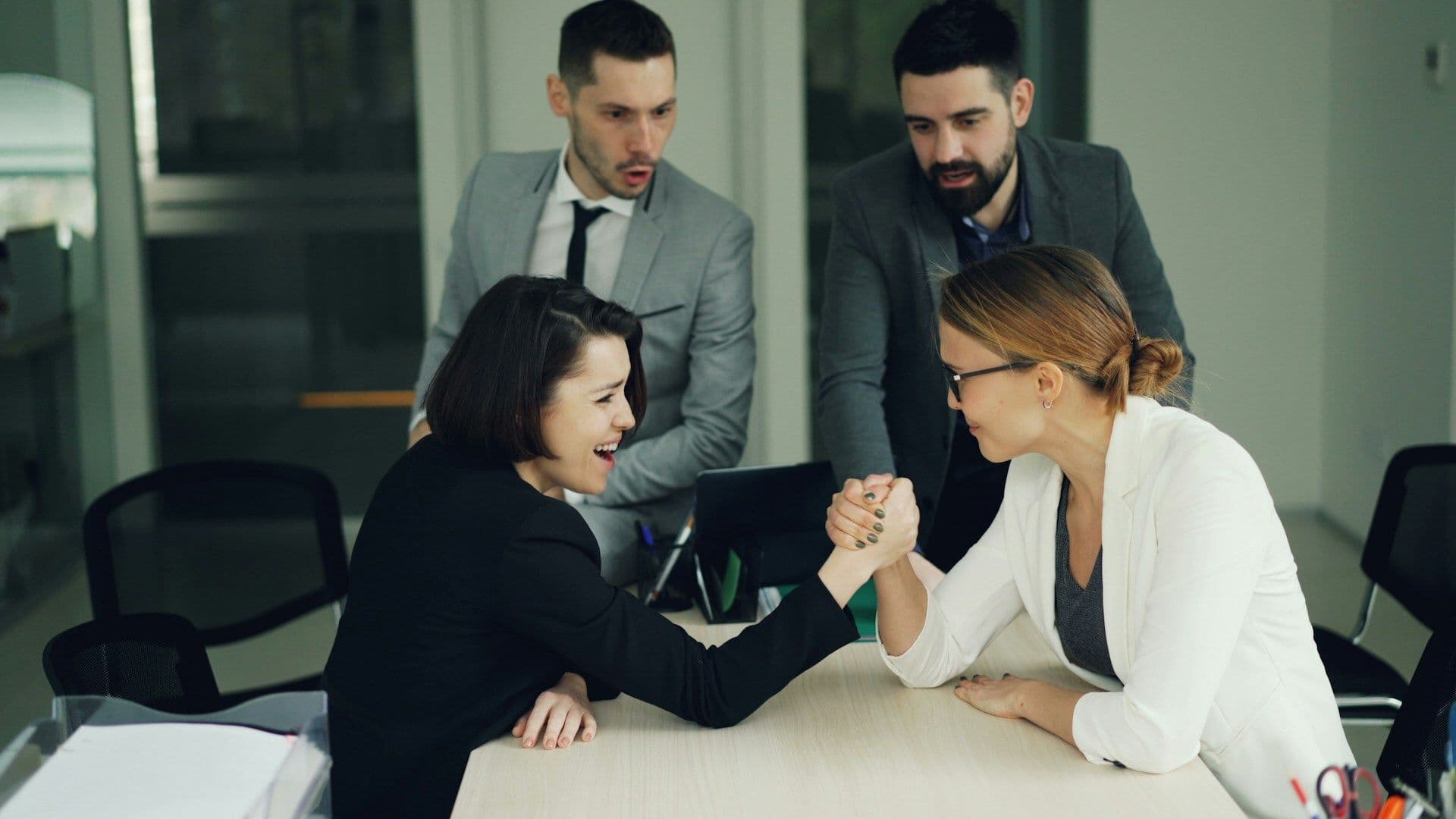 Two female colleagues arm wrestle during a team building activity