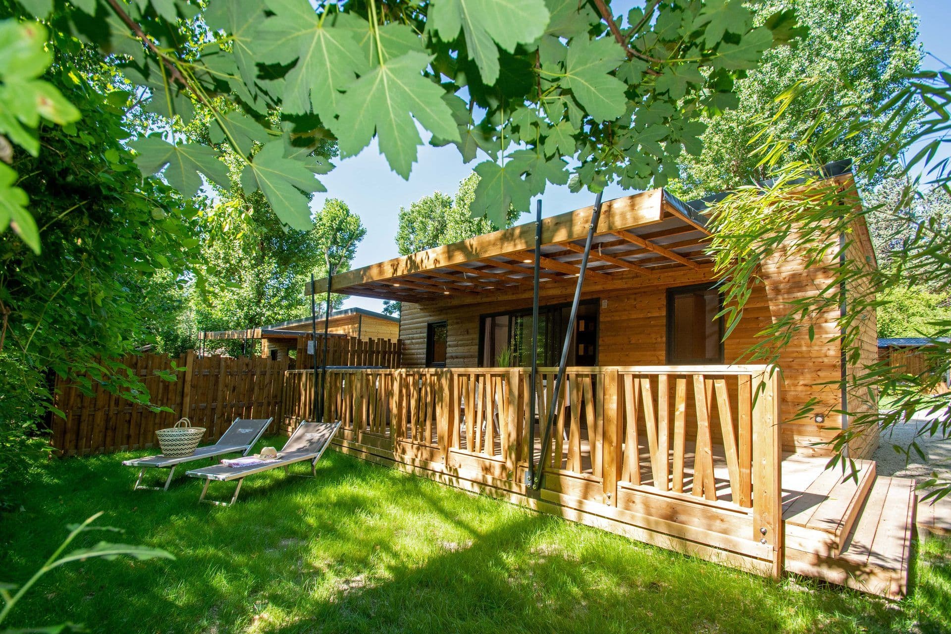Modern wooden cabins with spacious decks and a green lawn, perfect for a corporate retreat or team offsite.