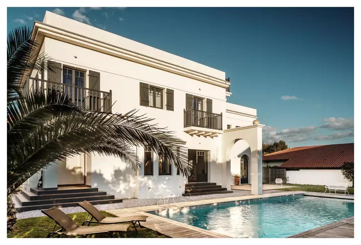Modern white villa with a swimming pool and palm tree, ideal for a corporate retreat or team offsite venue.