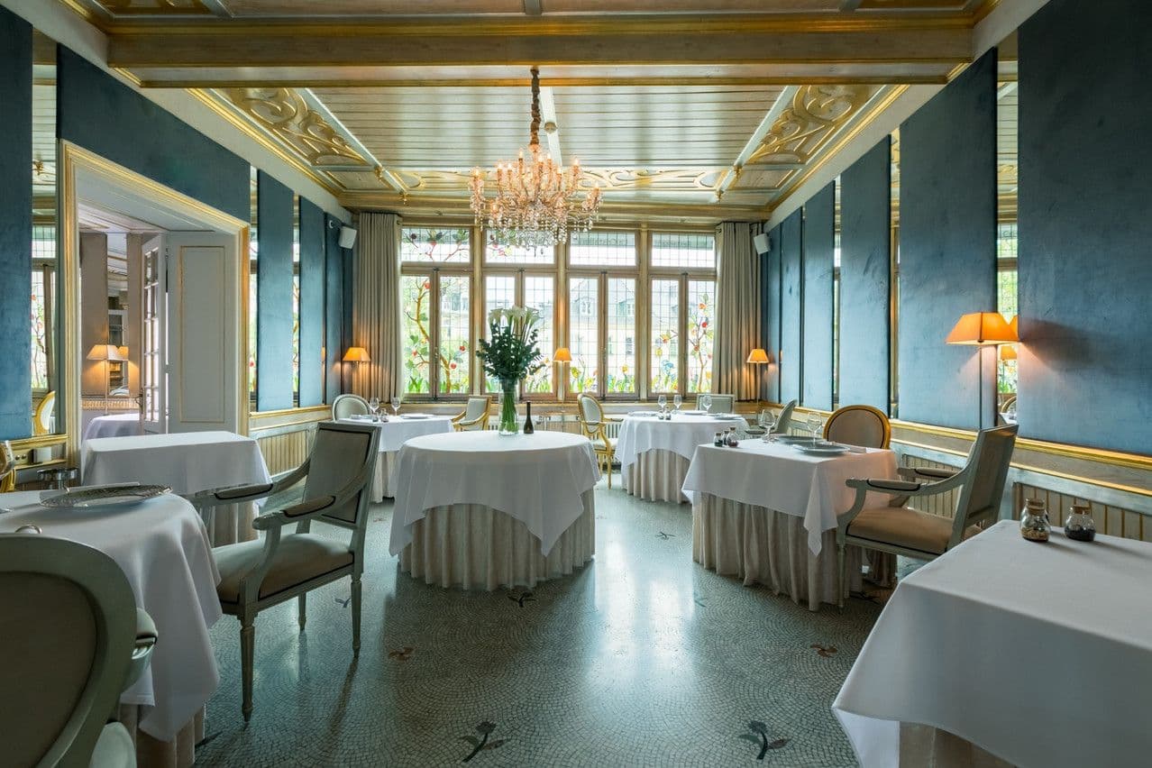 Elegant private dining room for corporate dinners, featuring blue walls, gold trim, and a crystal chandelier.