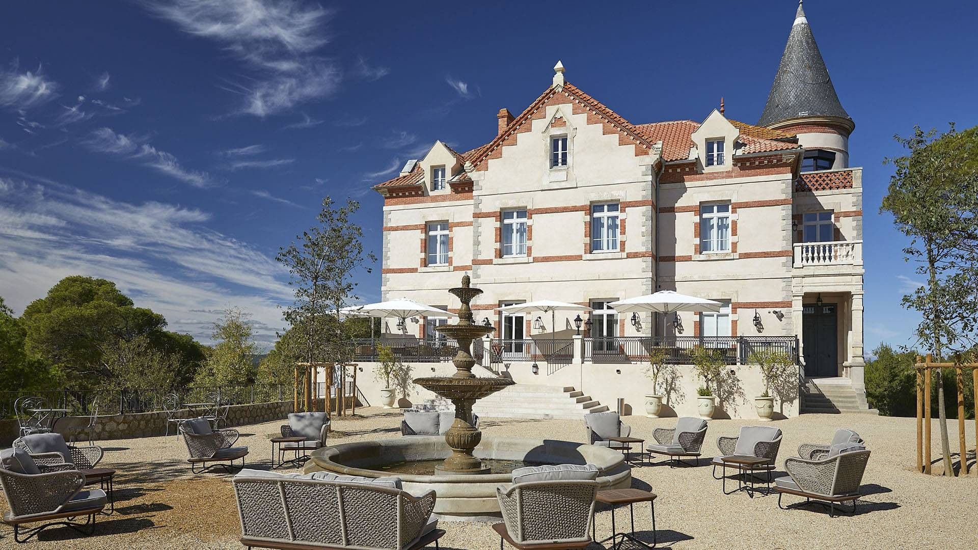 Elegant historic château-style venue with an outdoor courtyard, fountain, and comfortable lounge seating.