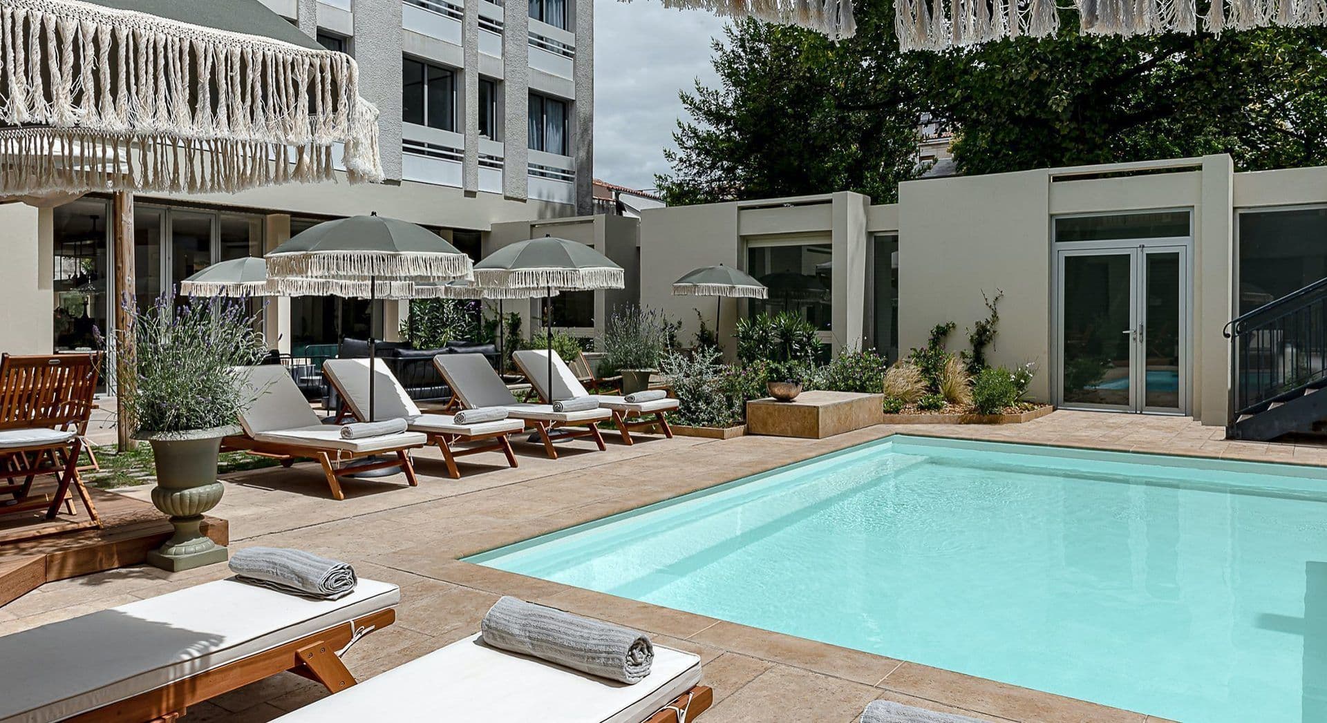 An inviting outdoor swimming pool area with lounge chairs and fringed umbrellas