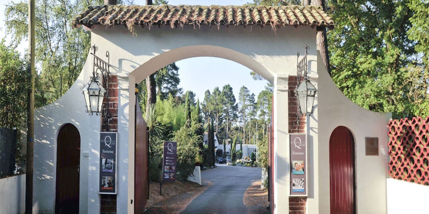 An elegant arched entrance with a tiled roof and lanterns leads to a secluded corporate event venue.