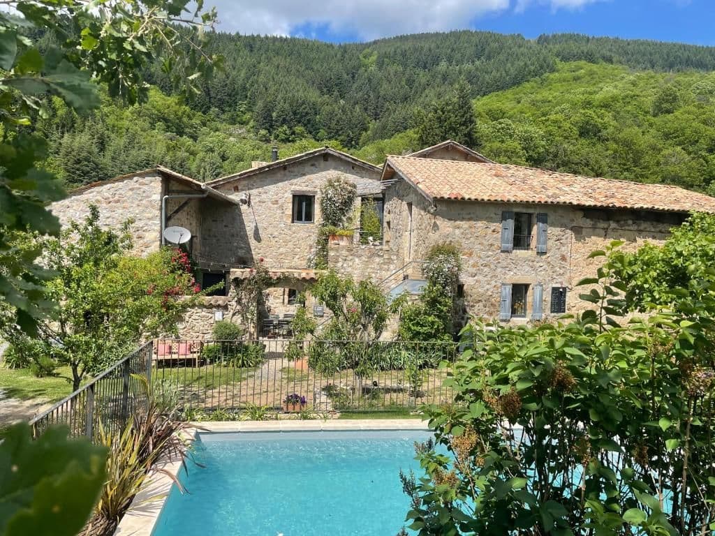 Historic stone corporate event venue with a pool, surrounded by green mountains