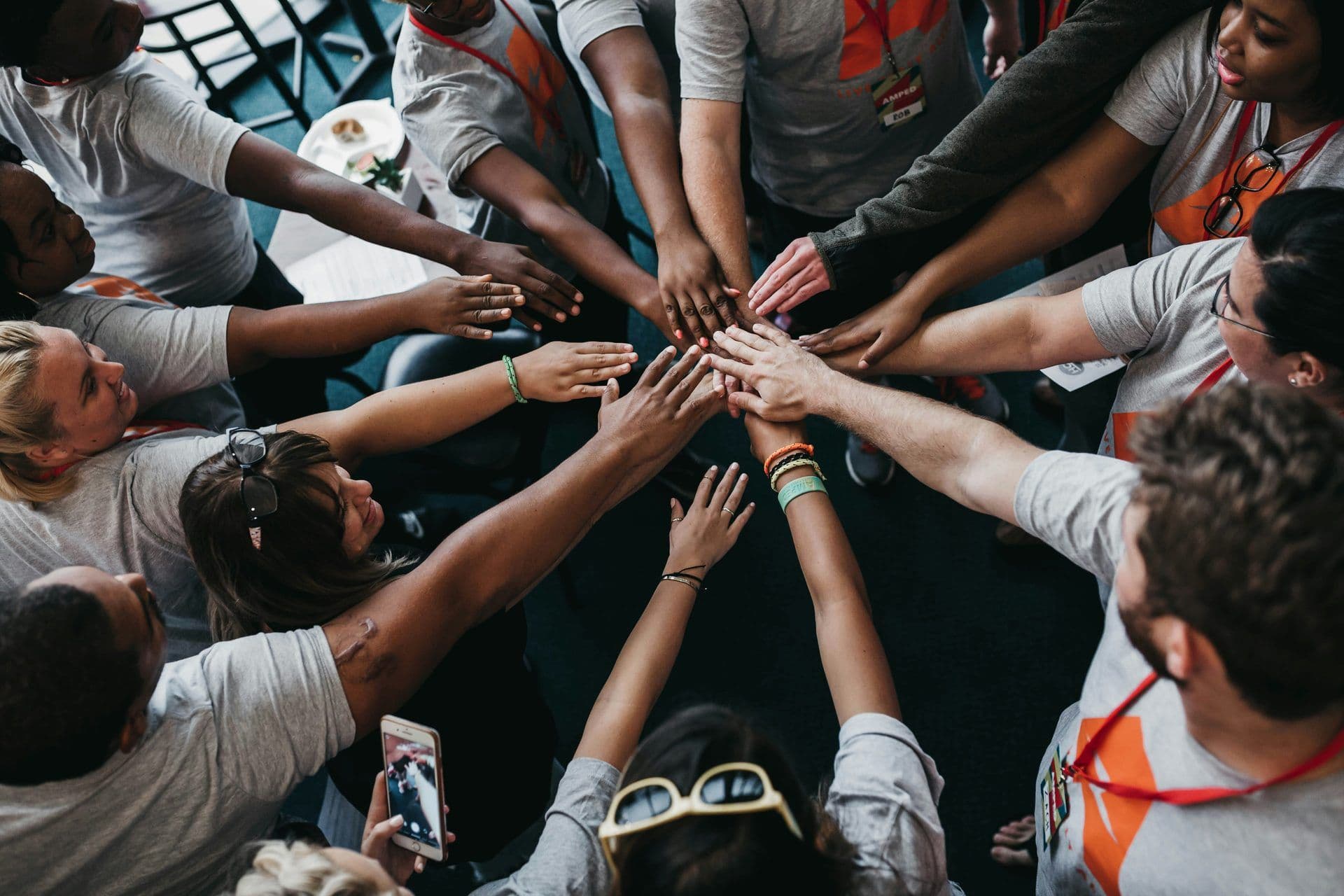 A diverse group of colleagues stacks their hands together in a circle during a team building workshop.