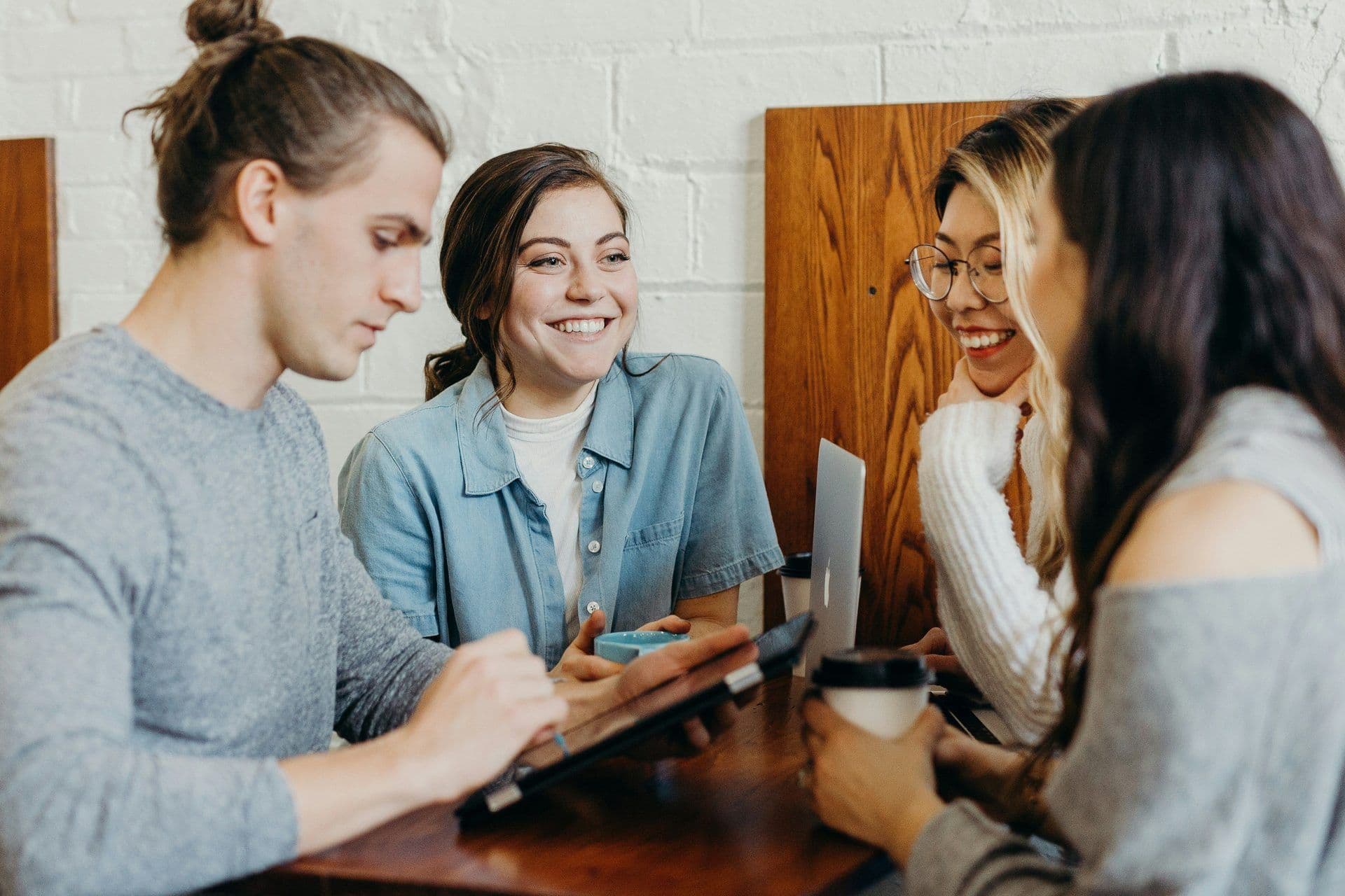 Young professionals discuss ideas around a table with a tablet and coffee, ideal for a small group workshop.