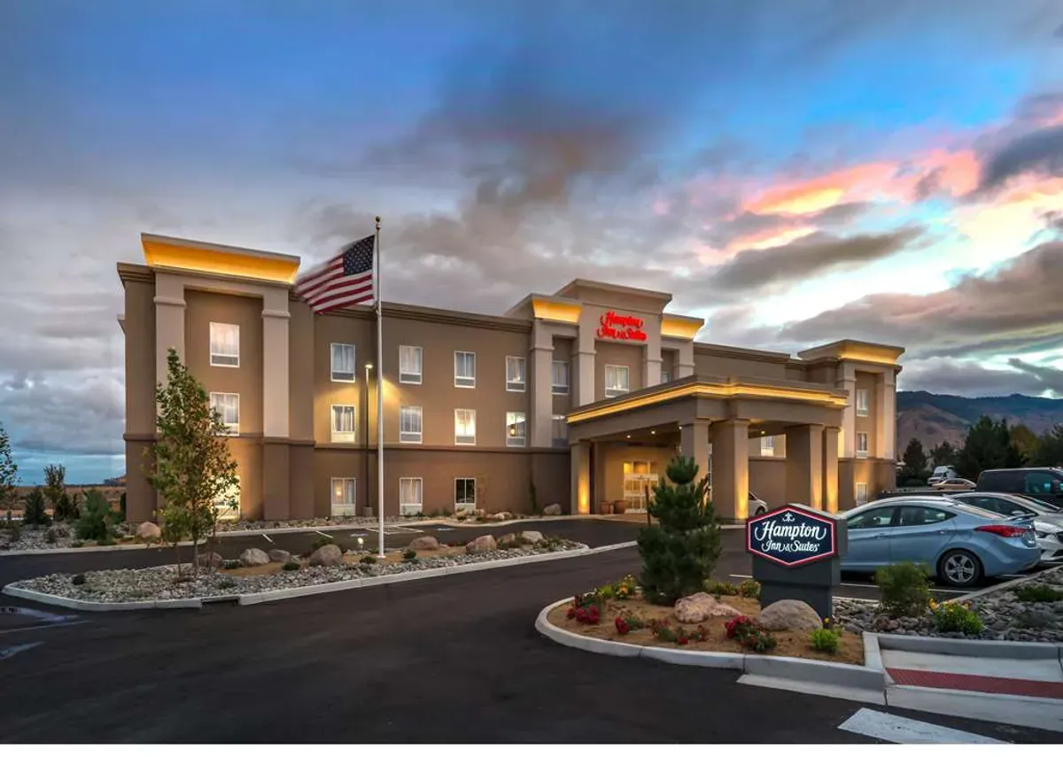 Exterior view of a Hampton Inn & Suites hotel at dusk, an ideal corporate event venue in the USA.