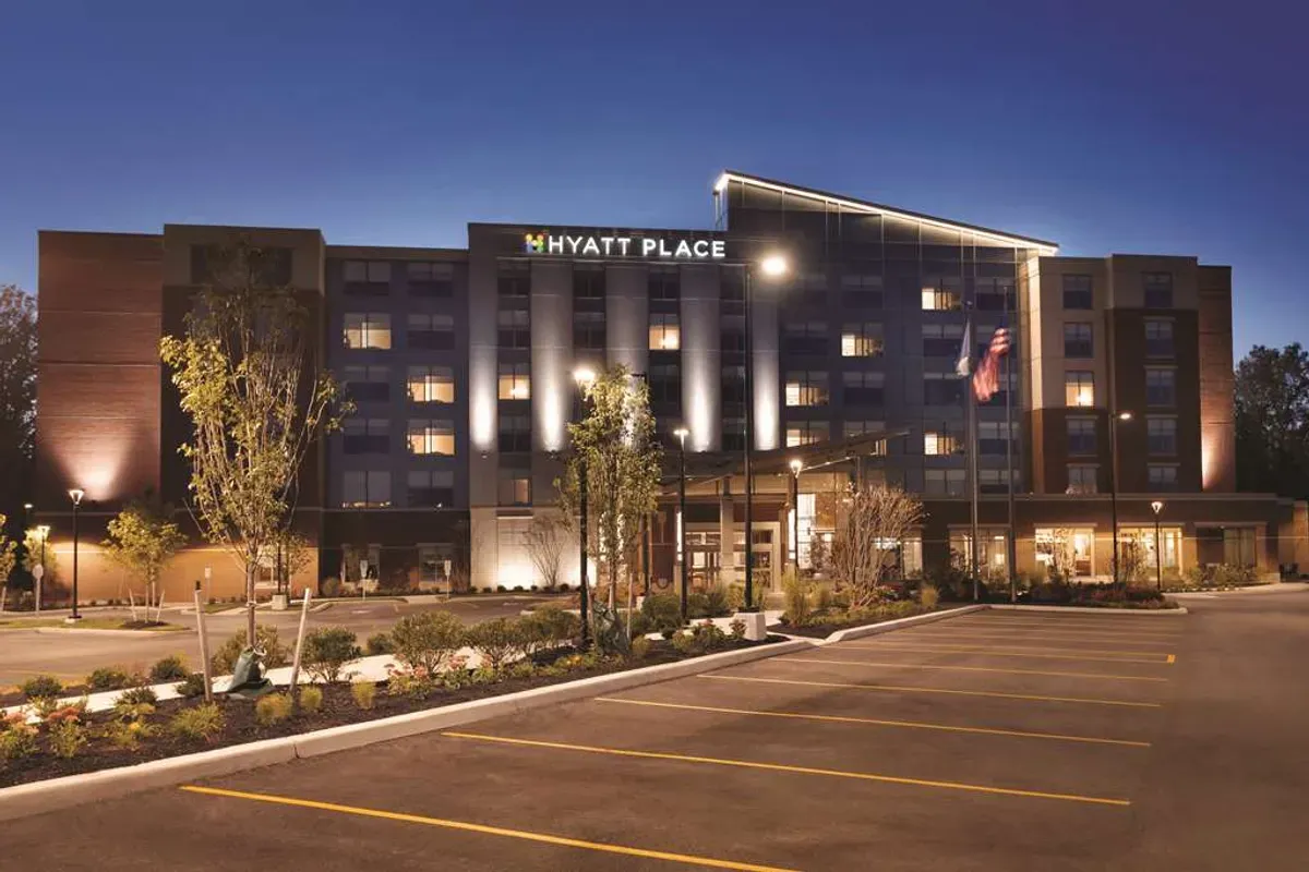 Hyatt Place hotel, an ideal corporate event venue, illuminated at night with a spacious parking area.