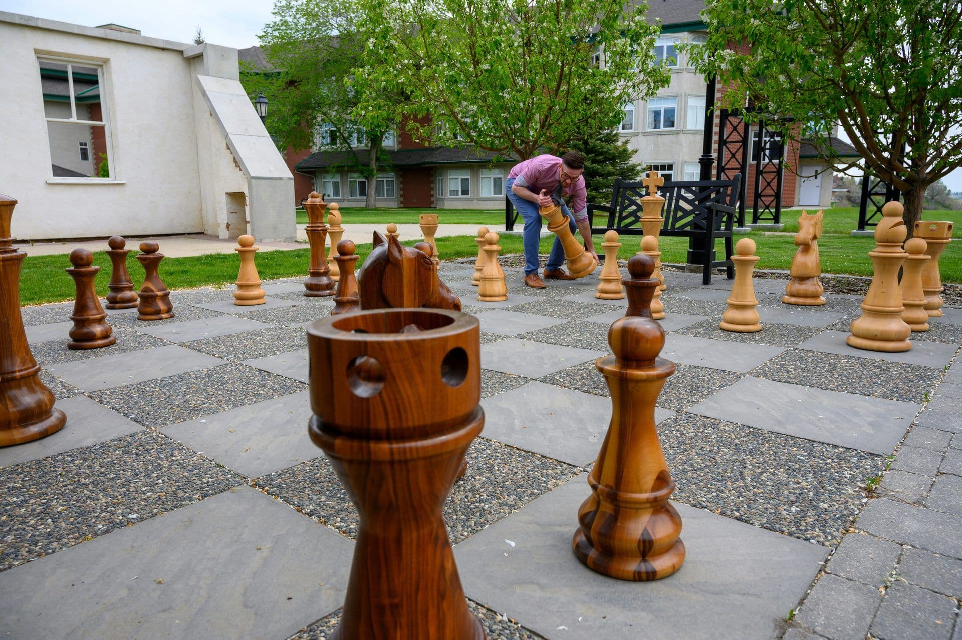 A man plays giant chess on an outdoor chessboard, perfect for a corporate team building activity.