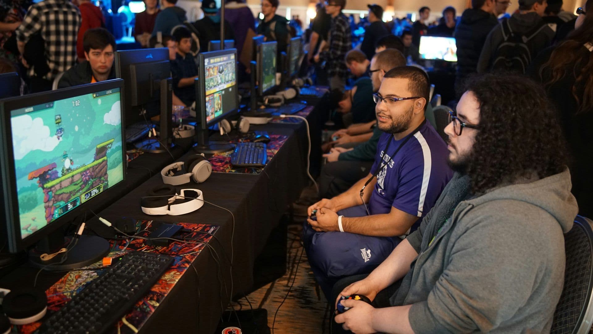 Attendees engage in a video game tournament, showcasing a fun corporate activity or team building event.