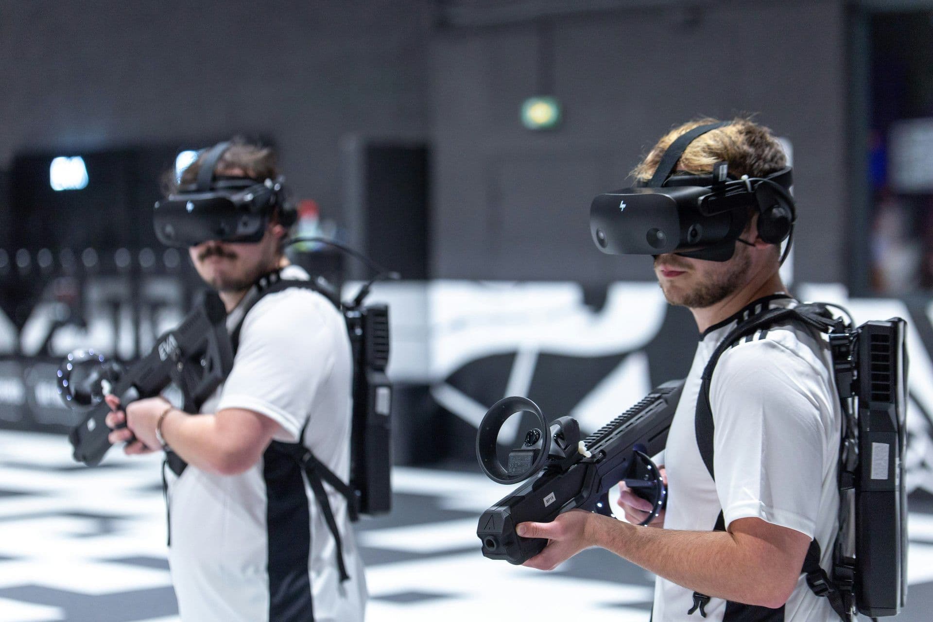 Two men in VR headsets with virtual reality guns engage in an immersive corporate team building activity.