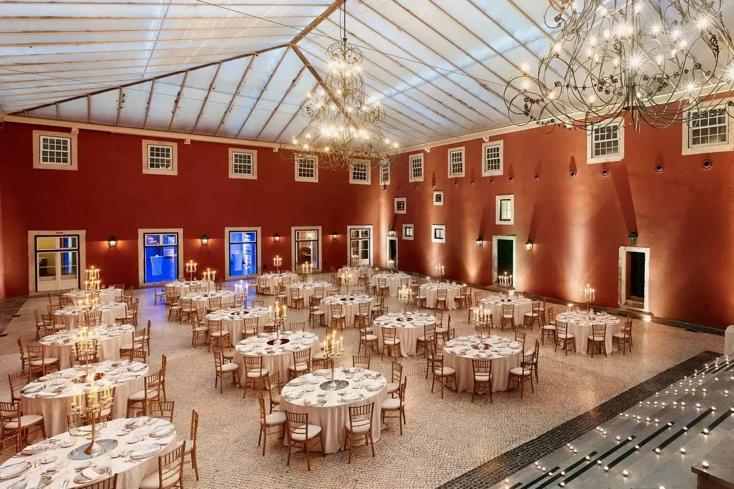 Grand ballroom venue with formal dinner setup, red walls, and a stunning glass ceiling for enterprise events.