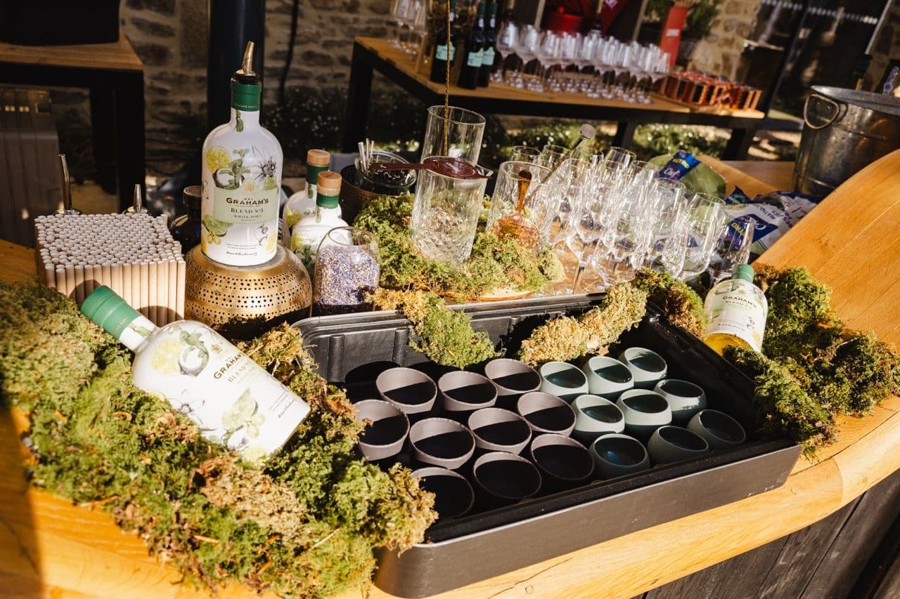 A rustic bar counter with Graham's white port bottles, empty glasses