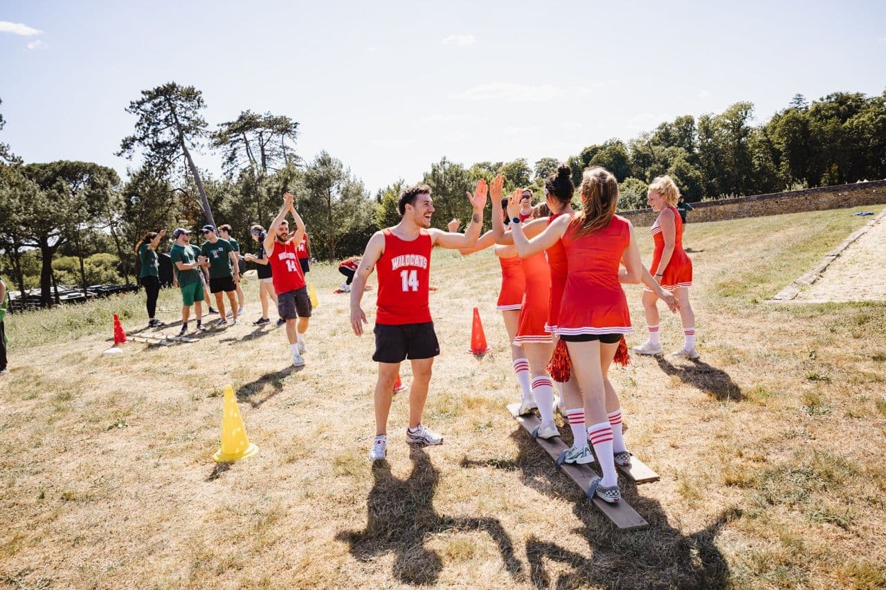 Teams high-fiving during an outdoor team building activity with plank walk challenge for a company offsite.