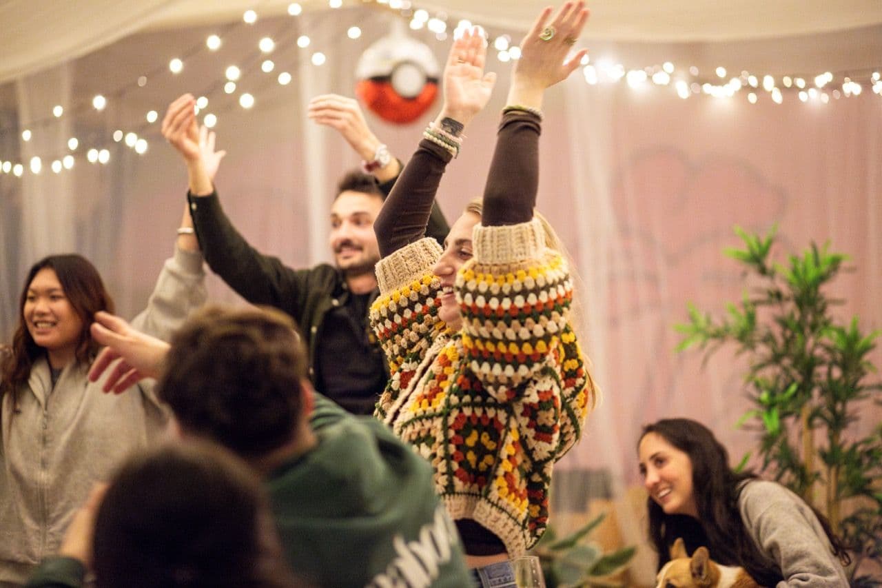 A diverse group of professionals enjoys a lively team building activity under festive string lights.