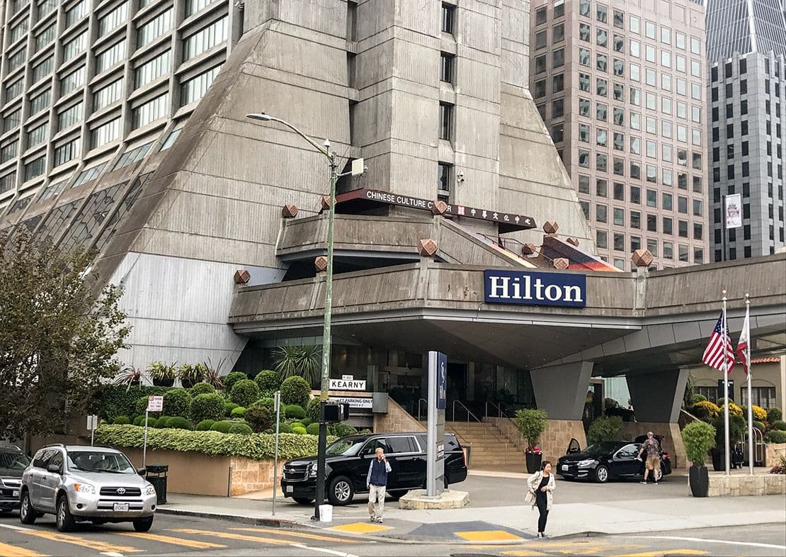 The brutalist architecture of the Hilton hotel entrance, a corporate event venue in San Francisco.