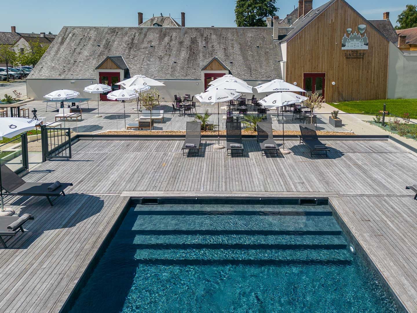An aerial view of a corporate event venue in France featuring a swimming pool, wooden deck