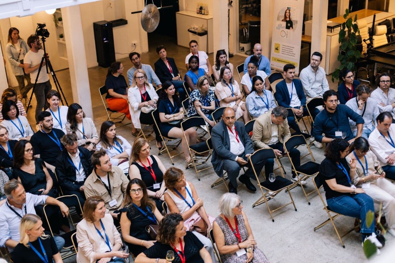 Diverse professionals attend a corporate seminar or workshop in a bright, open event space.