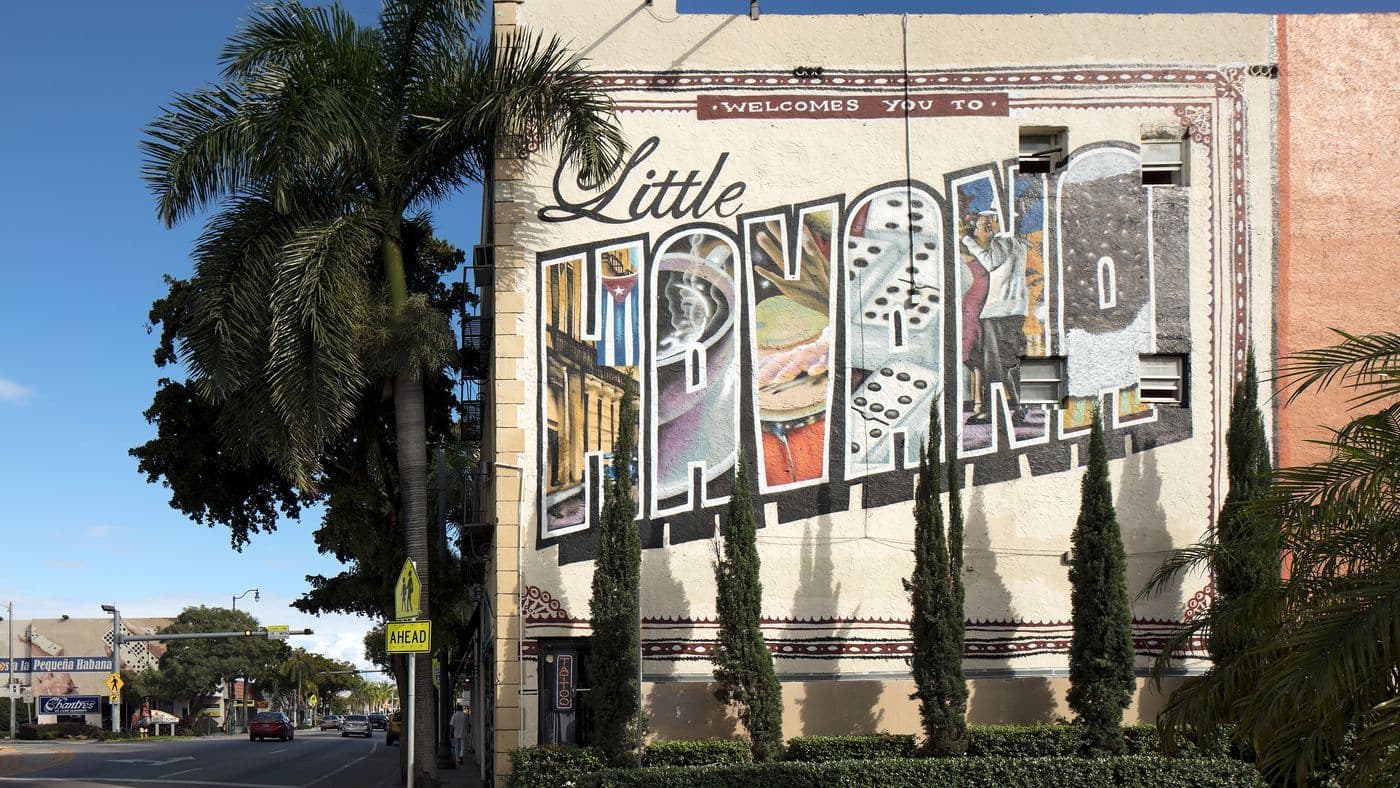 A vibrant 'Little Havana' postcard mural on a building in Miami, with palm trees and a street.