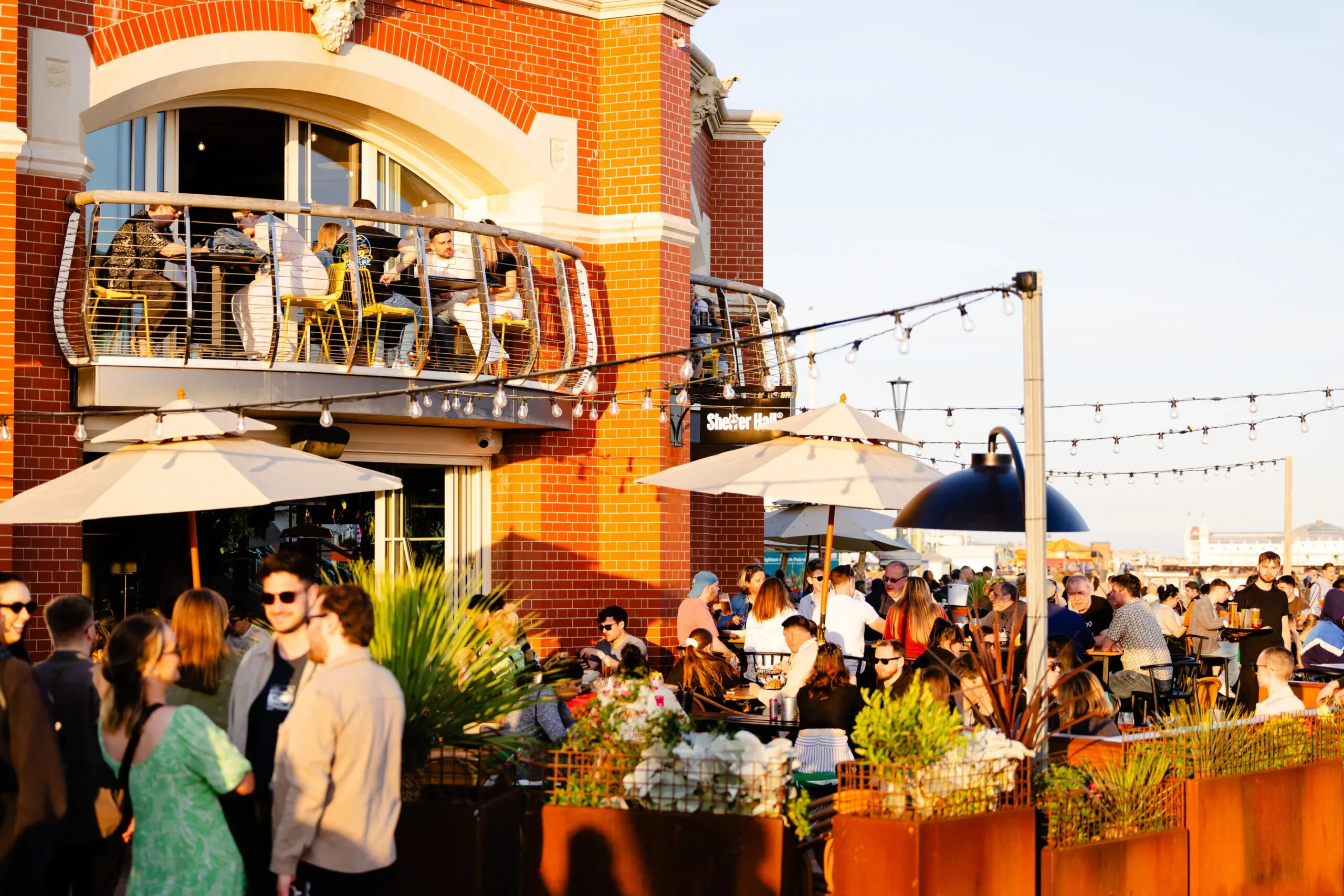Guests socialize on a vibrant waterfront terrace and balcony at Shelter Hall, a large group venue in Brighton.