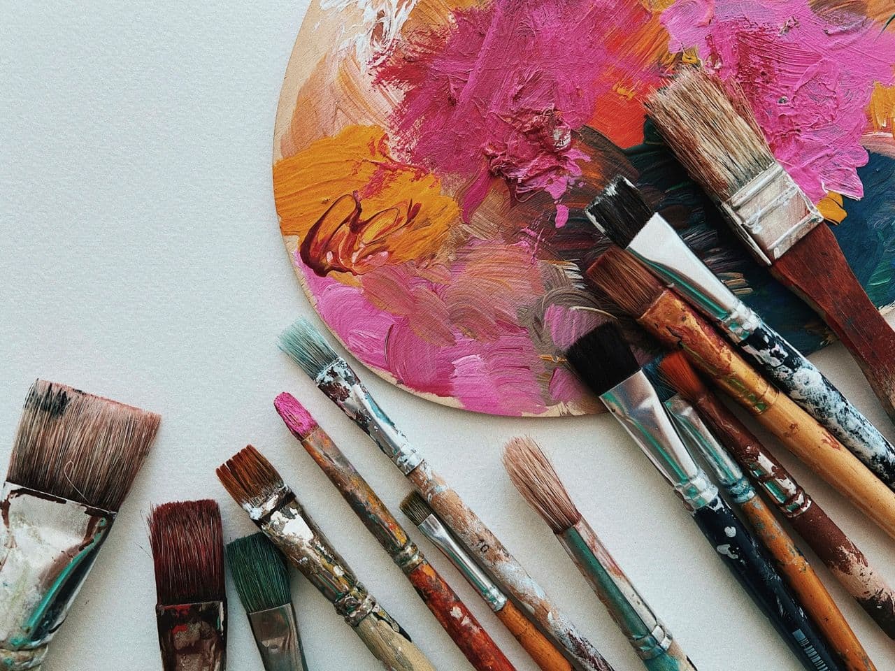 Close-up of an artist's palette with colorful paints and various paintbrushes